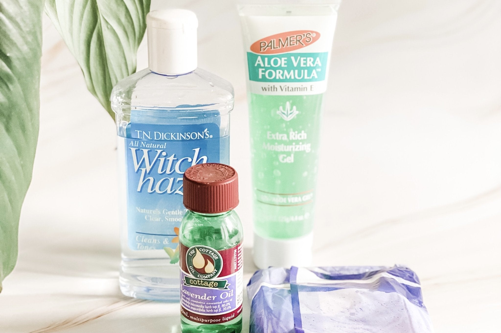 Flat lay of witch hazel, aloe vera, lavender oil and frozen padsicles in ice cube tray for DIY postpartum padsicles